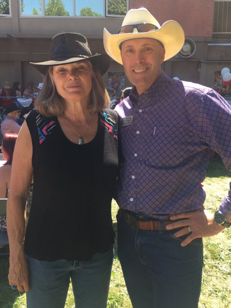 img des: Two people smiling for a photo, wearing cowboy hats